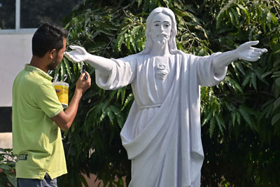 A worker cleans a statue of Jesus Christ and a cross at a church in Agartala on December 24 ahead of Christmas celebrations.